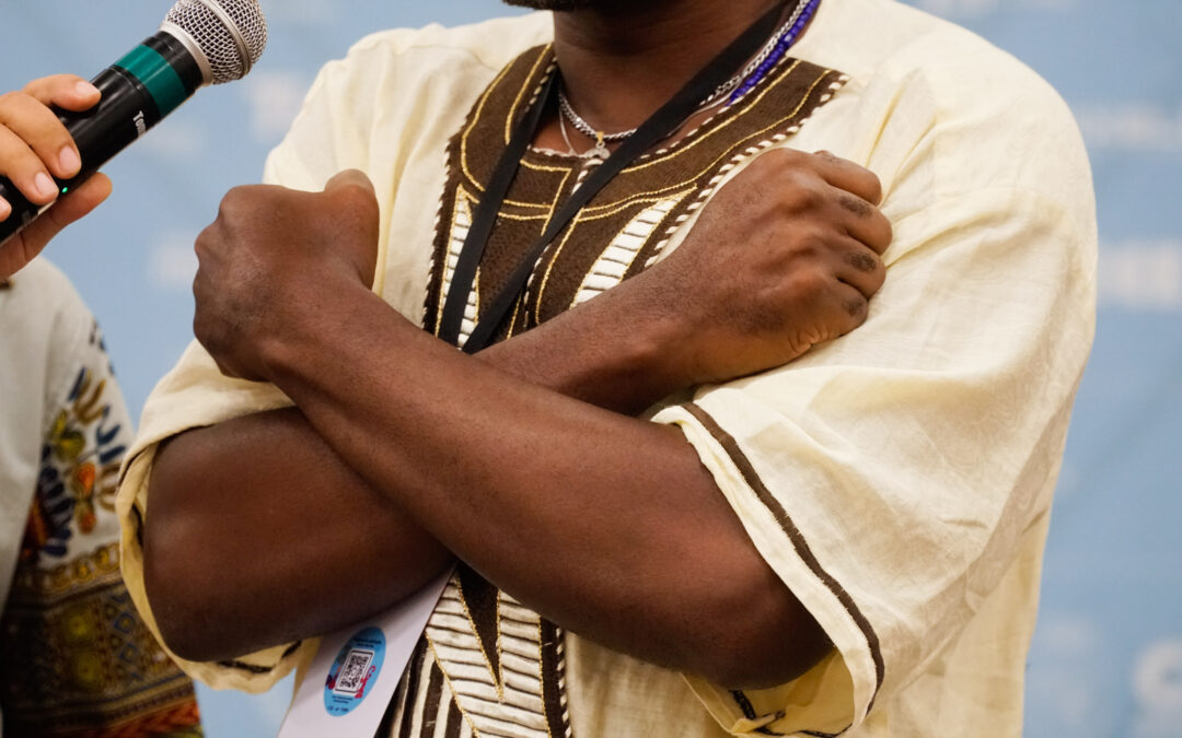 Foto de homem negro cruzando os braços em forma de X sobre o peito. Remete a um símbolo de resistência negra.