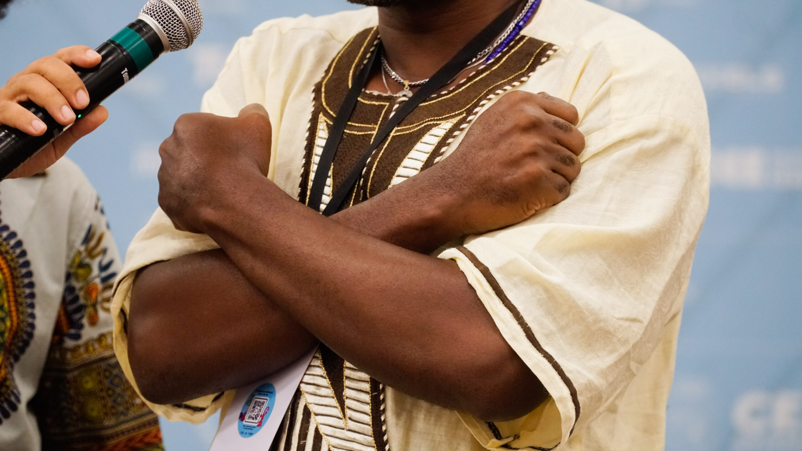 Foto de homem negro cruzando os braços em forma de X sobre o peito. Remete a um símbolo de resistência negra.