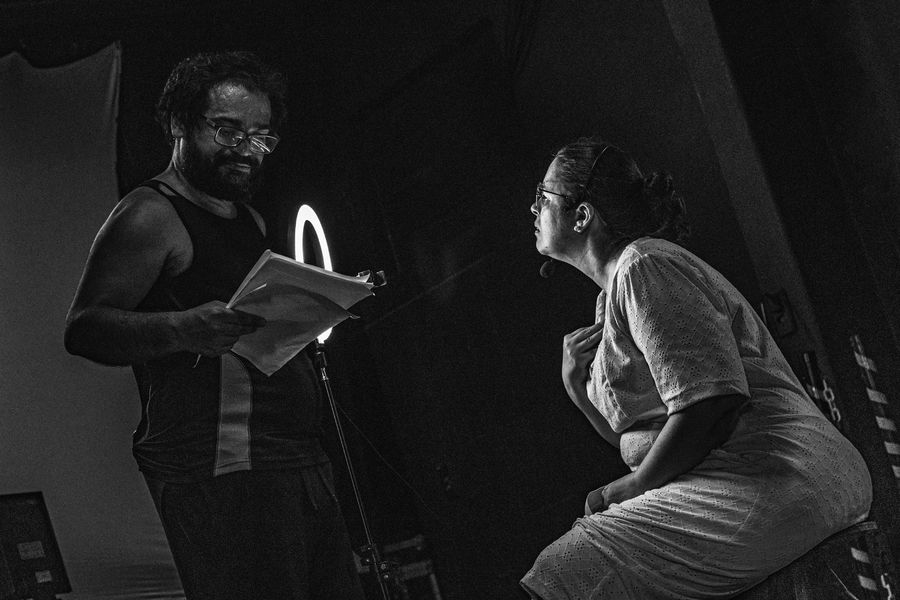 Um homem negro e uma mulher branca, ambos de óculos, , em cena numa peça teatral, numa foto em preto e branco. Foto: Tim Oliveira