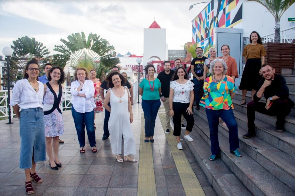 Pessoas de várias raças, estaturas e tipos físicos diferentes, com roupas coloridas, posam para a foto.