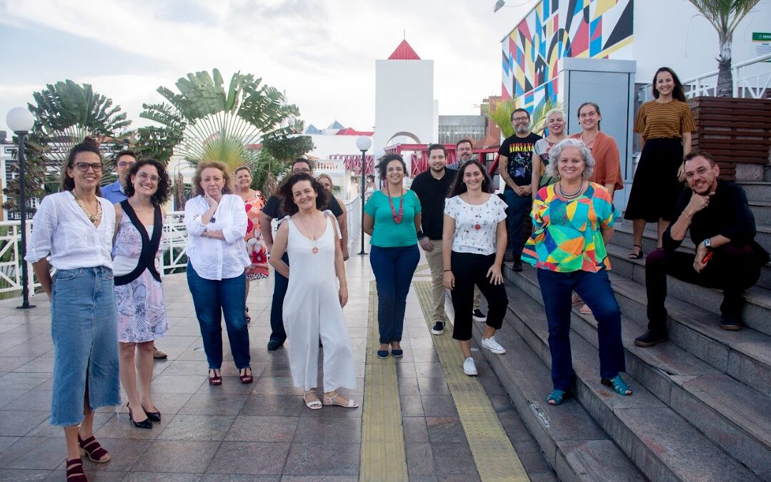Pessoas de várias raças, estaturas e tipos físicos diferentes, com roupas coloridas, posam para a foto.