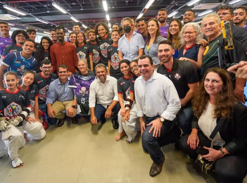 A foto contém mais de 10 pessoas, de raças diversas, homens e mulheres, vestidos de cores e estilos variados.