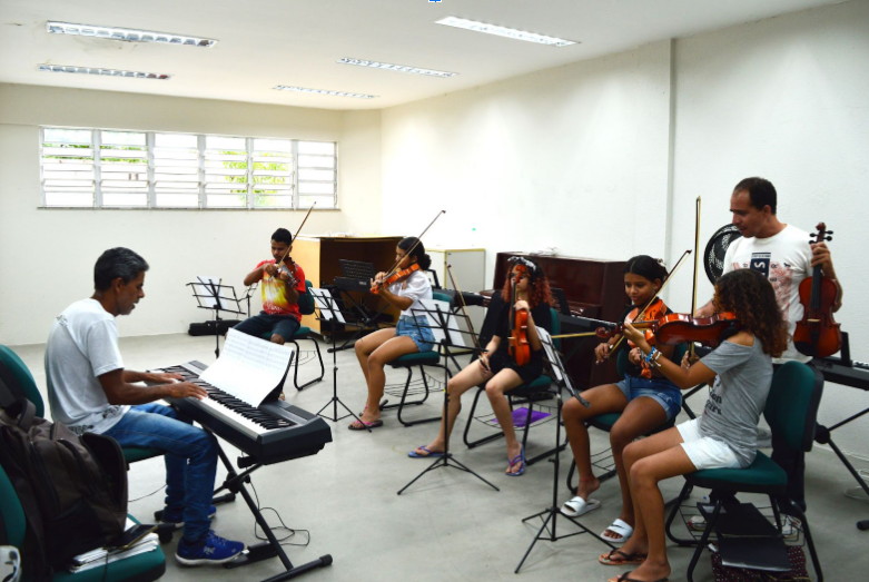 Fotos de alunos da Vila da Musica, escola da secult ceará gerida pelo idm. os estudantes estão em aula de música. Há teclado e violino.
